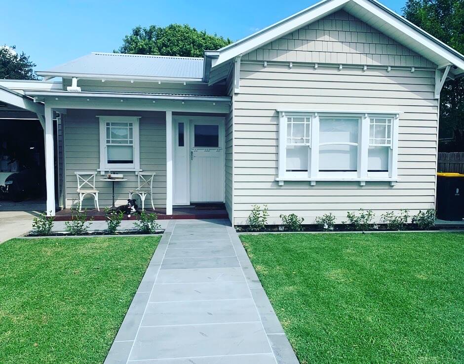 A white weatherboard home with freshly mowed lawn