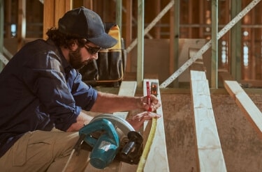 A builder measuring wood to cut