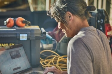 A construction worker on-site using Buildxact on a laptop