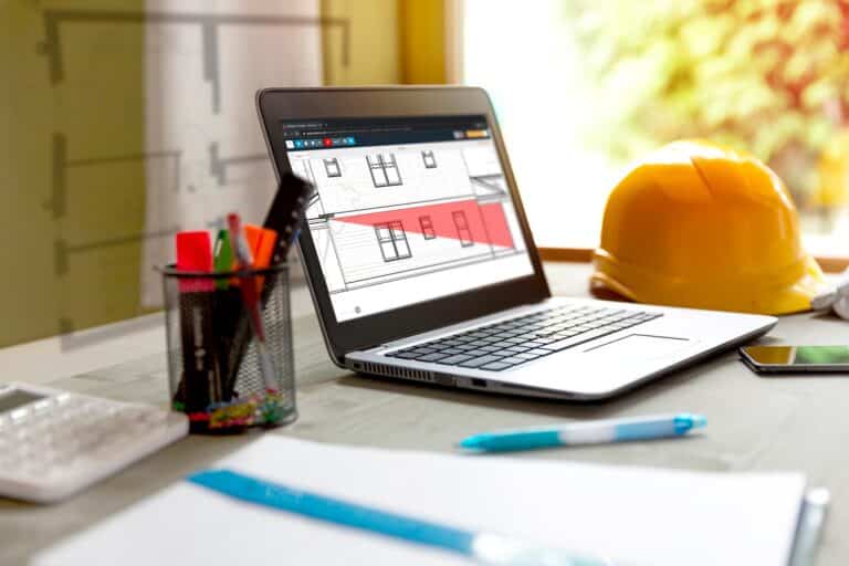 A takeoff being done with Buildxact via laptop on a desk with a hardhat and stationary