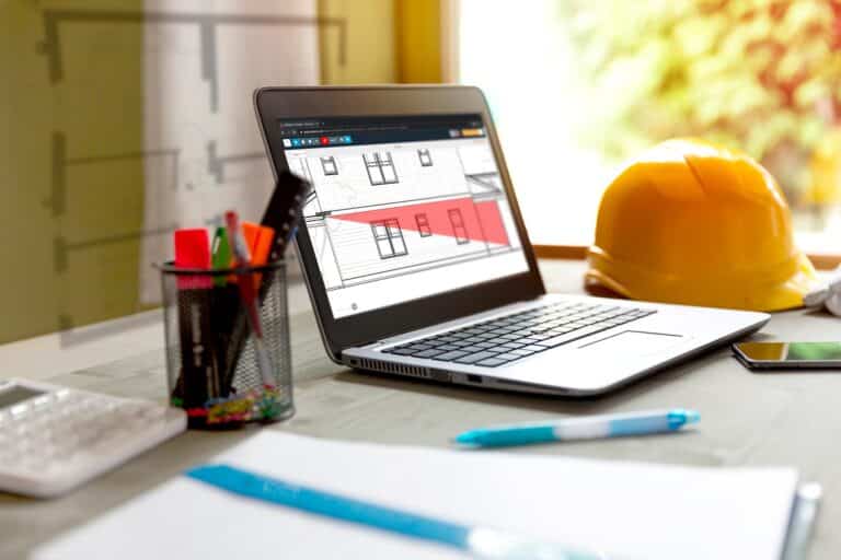 A takeoff being done with Buildxact via laptop on a desk with a hardhat and stationary
