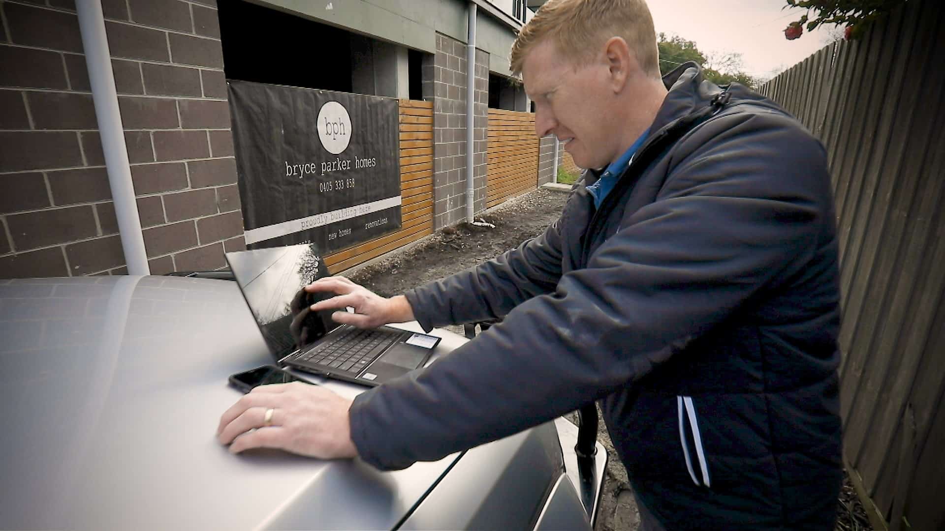 Buildxact customer Bryce Parker using a laptop on a construction site