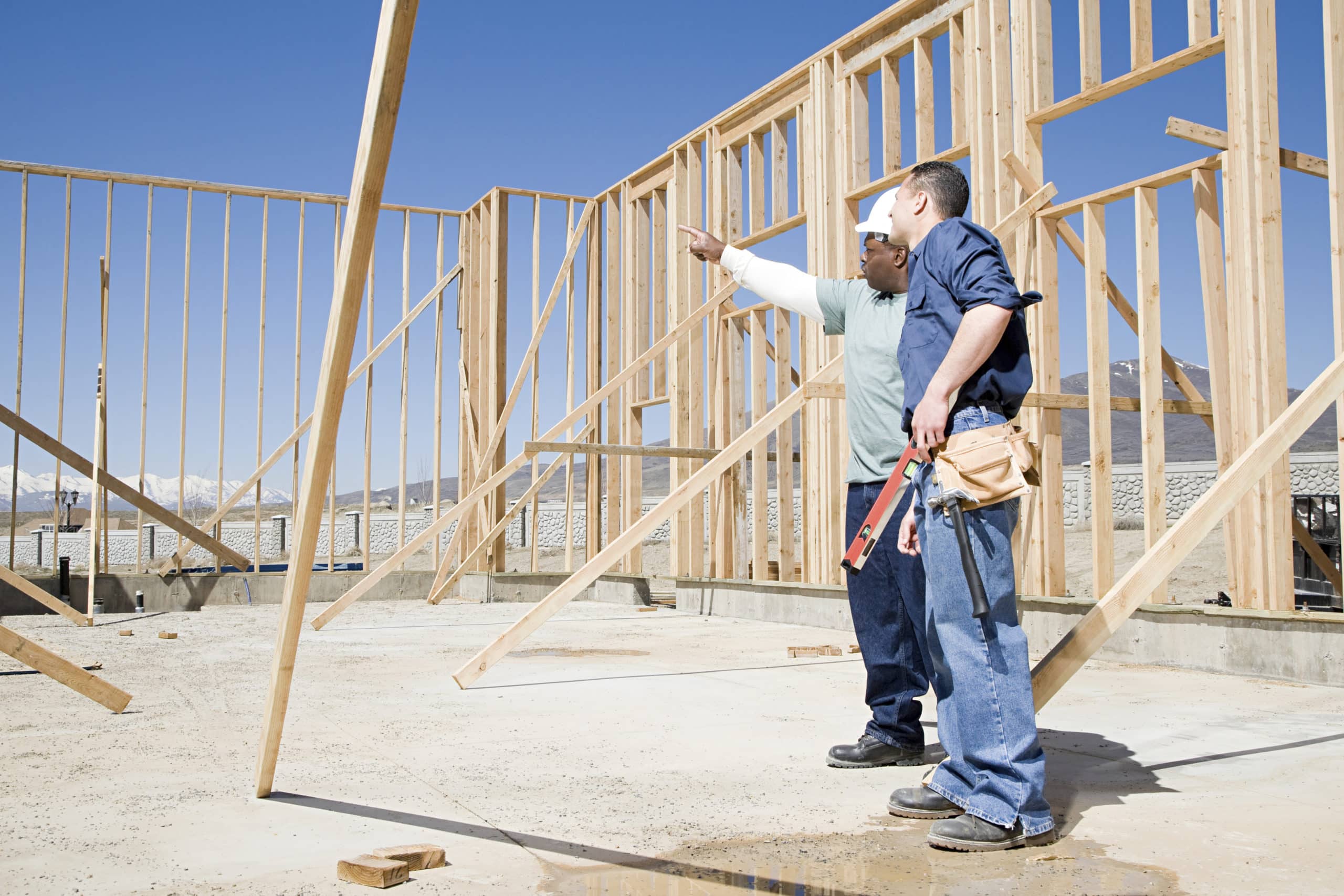 Two builders on site surrounded by timber framing and pointing