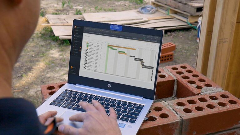 Buildxact customer using the Buildxact scheduling feature on a laptop at a job site