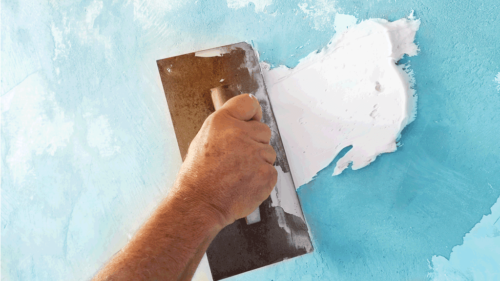 A builder applies plaster to a wall during a home construction project.