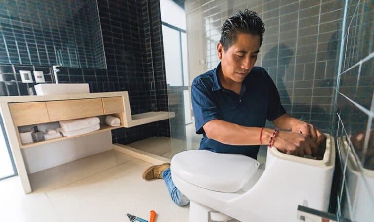 A plumber working on a toilet installation in a bathroom