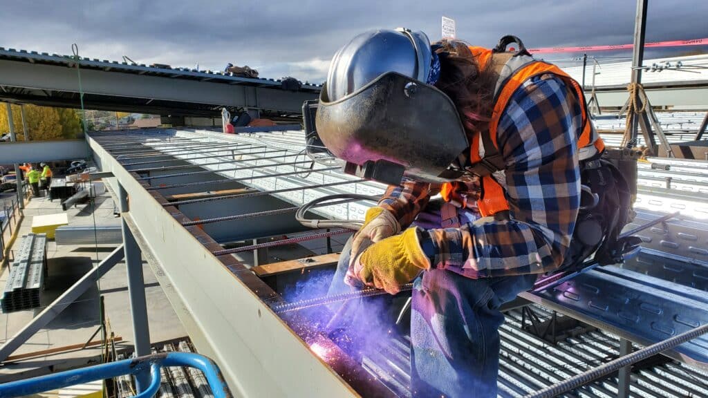 A steelworker using a welder on a metal roof