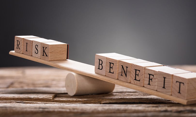 Blocks spelling risk and benefit on a balancing board