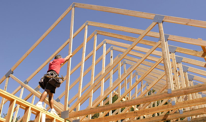 Roofer working on framing against a blue sky