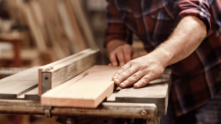 A builder safely operates a table saw at a home construction site.