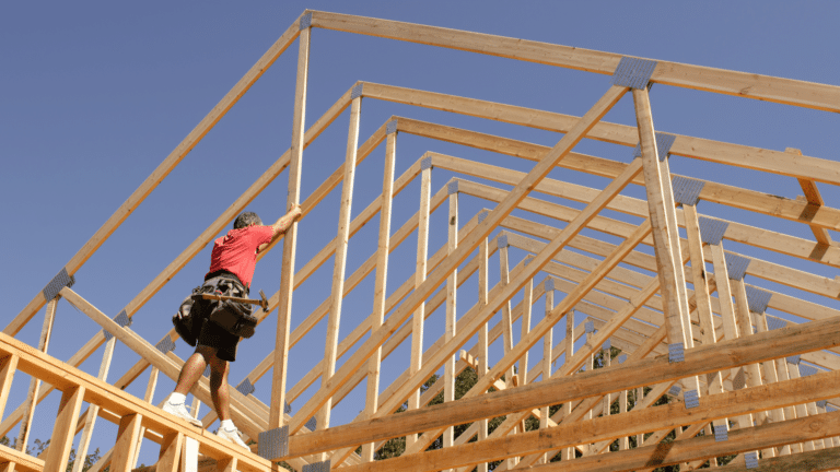 Roofer working on framing against a blue sky