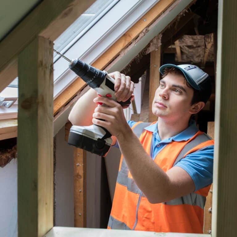 A builder uses a power tool on a construction site.