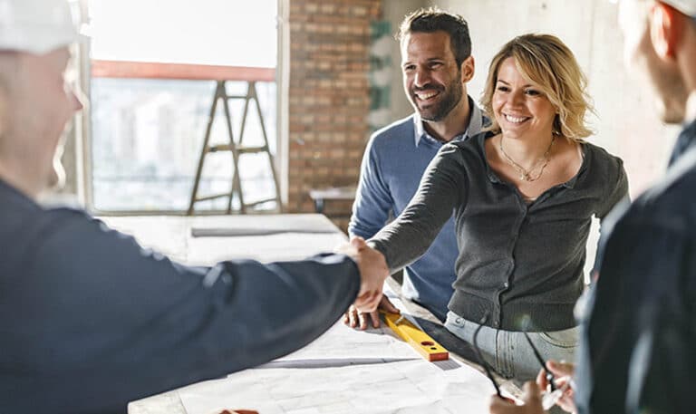 A builder and a customer shaking hands at a job site