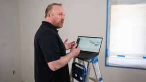Customer discusses Buildxact with his laptop perched on a ladder
