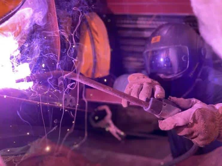 A welder is working on a piece of iron while wearing protective headgear