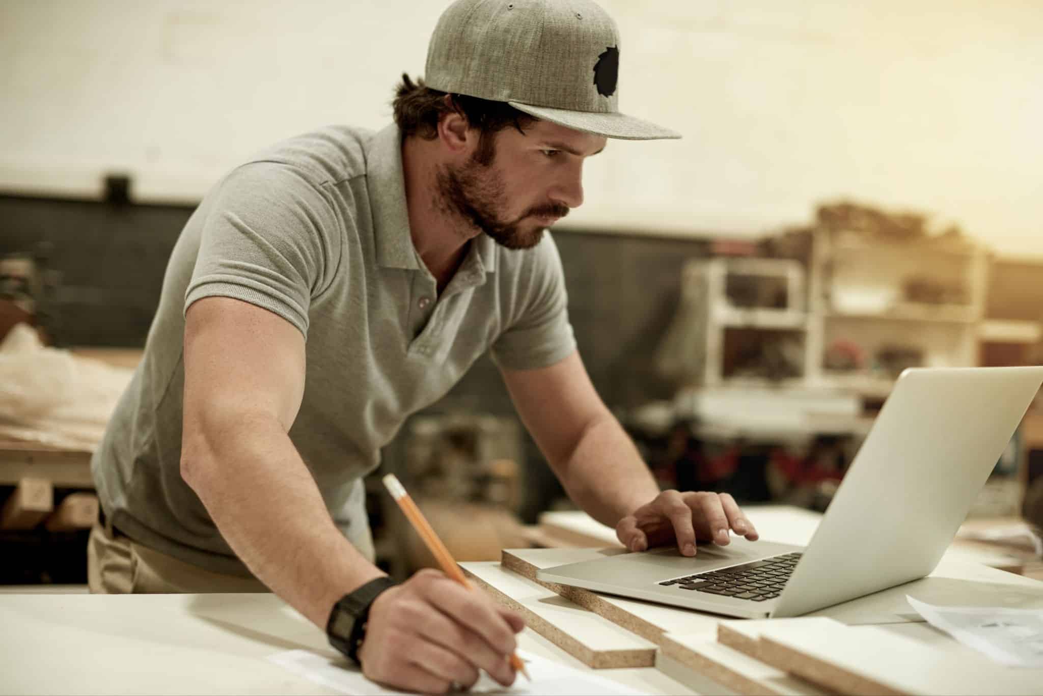 Builder working on a laptop and manually